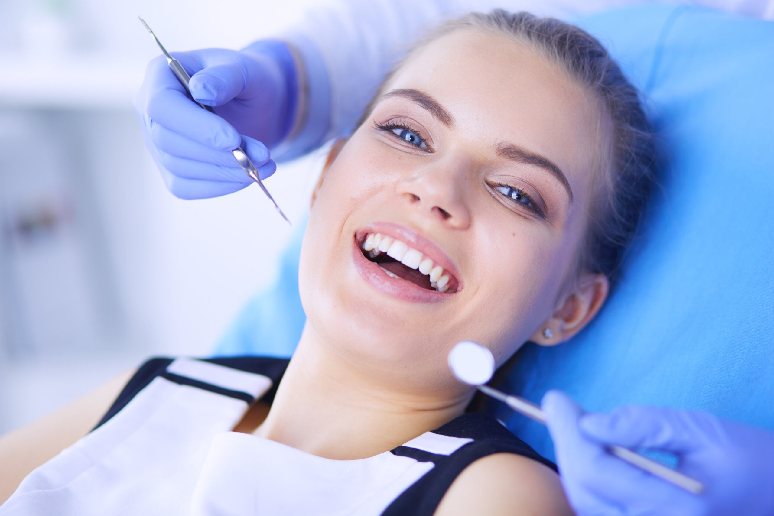 Young Female patient with open mouth examining dental inspection at dentist office