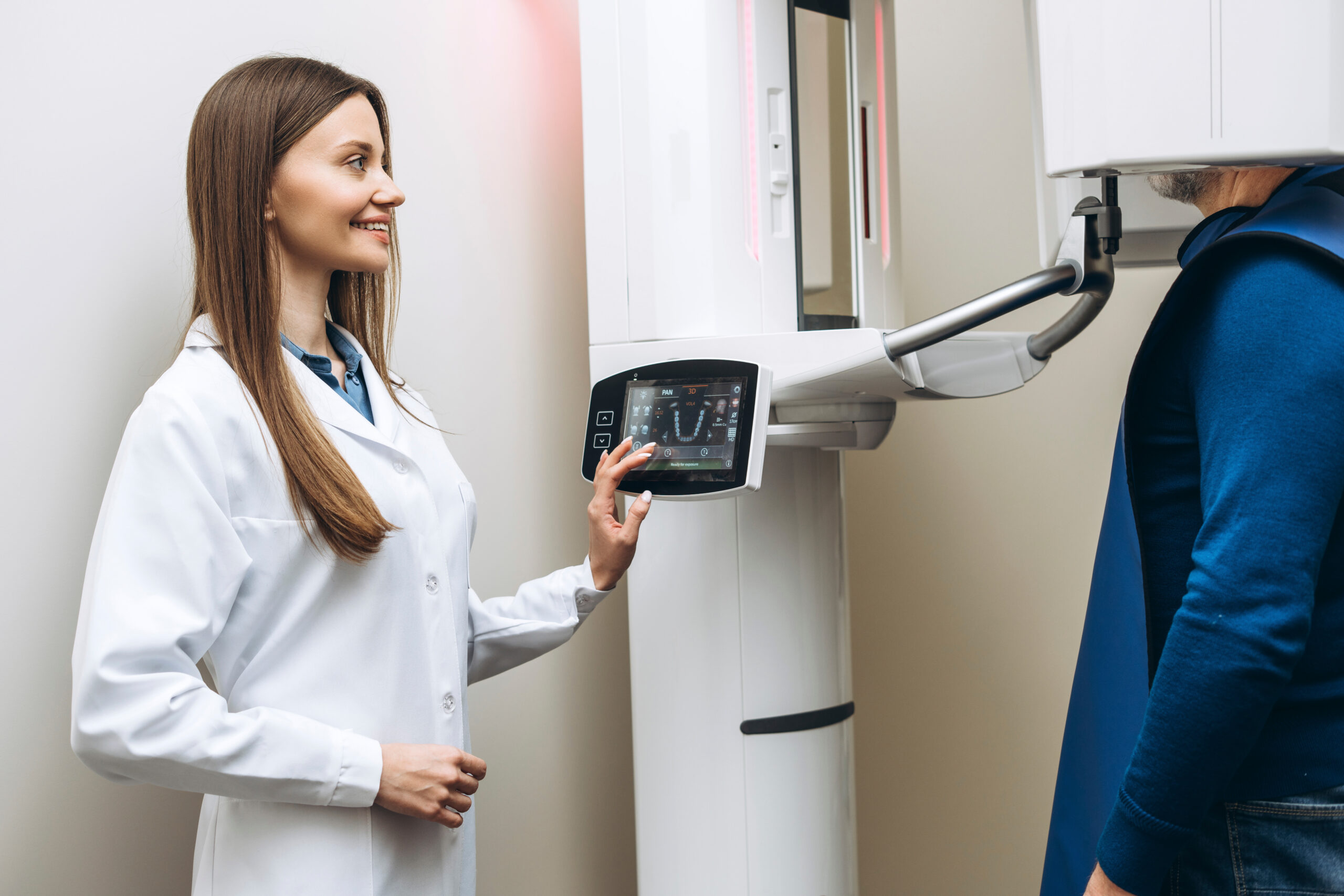 Professional female dentist using special equipment and making panoramic dental x-ray for male patient. Computer dental diagnostics