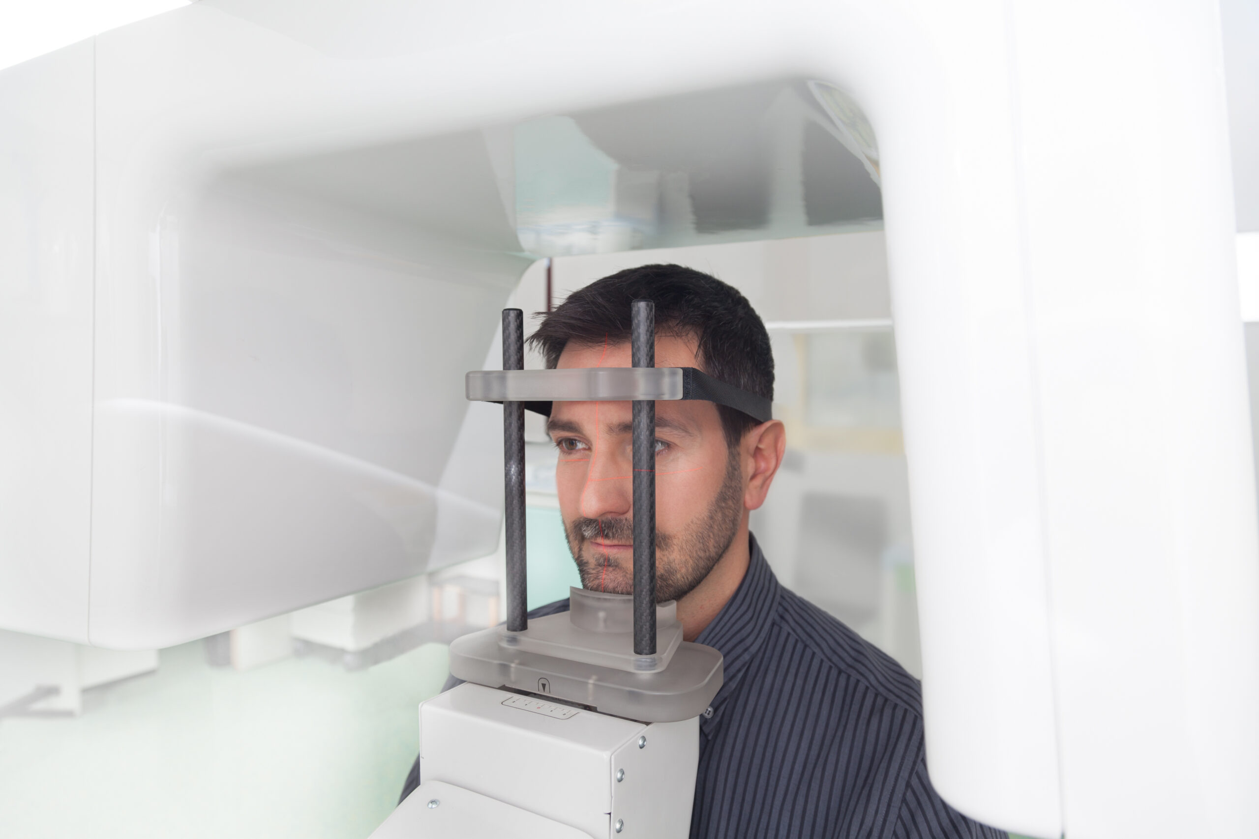 Young man portrait having panoramic digital X-ray of his teeth in the dental office.