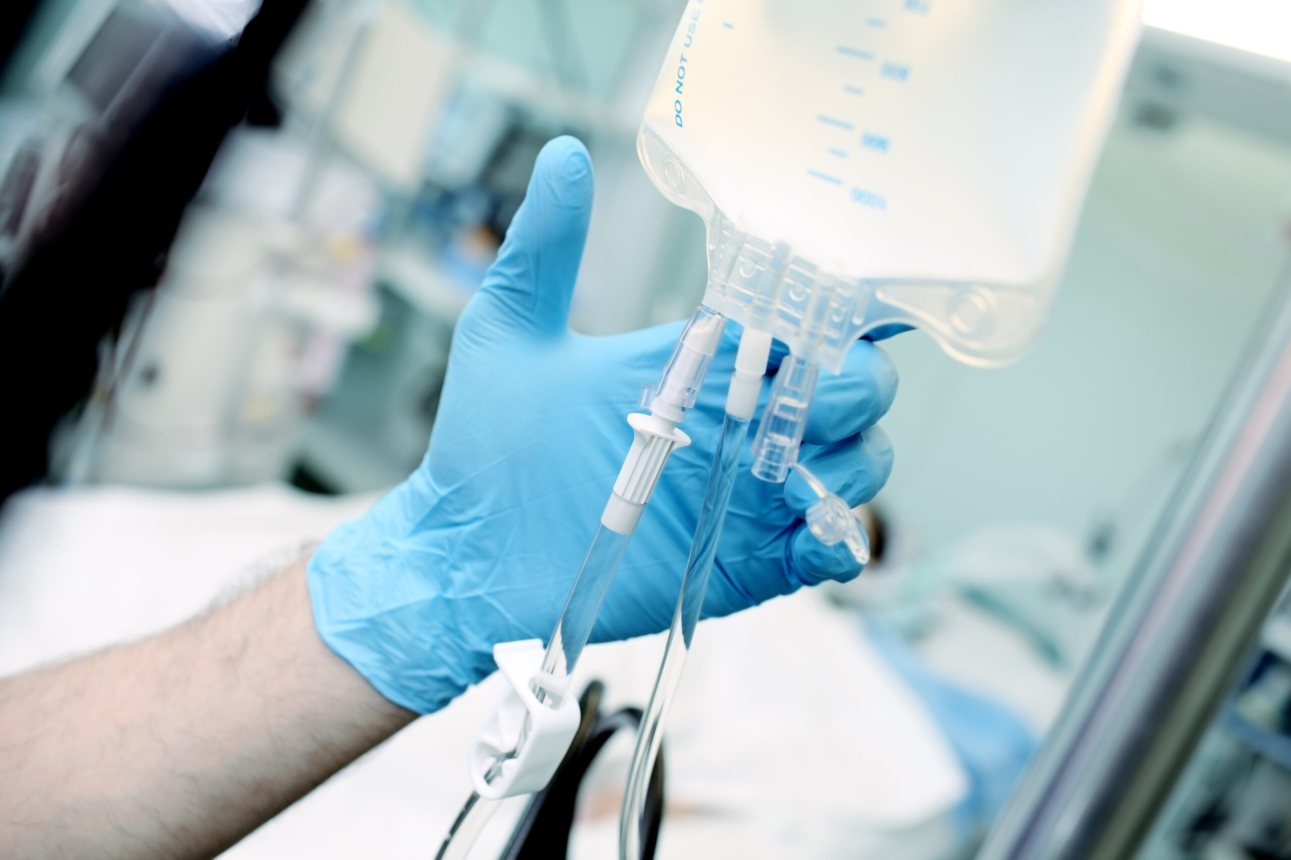 Male medical worker regulate the intravenous drip system at the patient bed in the critical care unit.